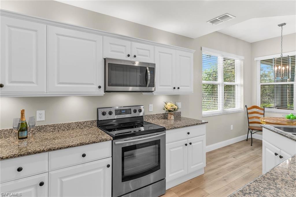 4705 Hawks Nest Way, Unit F101 Naples, FL 34114 - Photo 8 of 41 a kitchen with granite countertop a stove a sink and a microwave