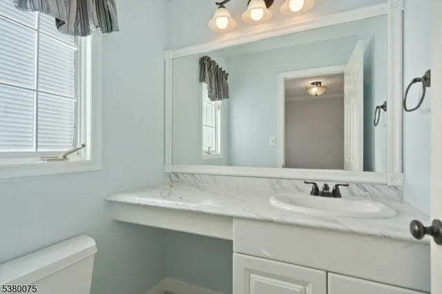 a bathroom with a granite countertop sink a toilet and a mirror