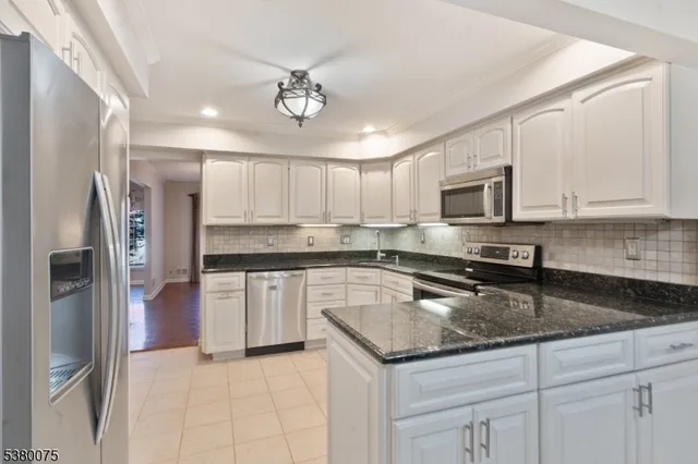 a kitchen with kitchen island granite countertop stainless steel appliances a sink a stove cabinets and a counter top space