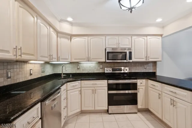 a kitchen with granite countertop white cabinets and stainless steel appliances