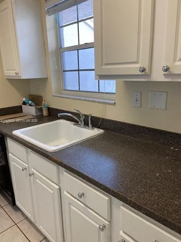 a kitchen with granite countertop white cabinets and a sink