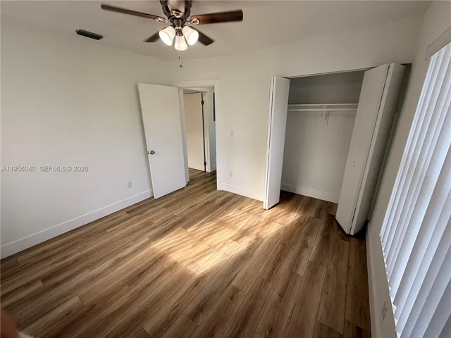 a view of empty room with wooden floor and fan