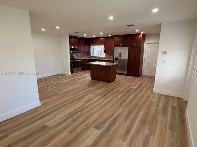 a kitchen with stainless steel appliances kitchen island granite countertop a refrigerator and a stove top oven