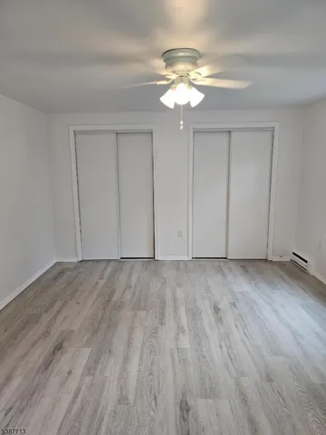 a view of an empty room with wooden floor and chandelier