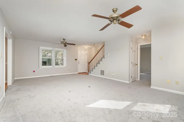 an empty room with ceiling fan and window