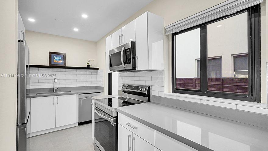 3764 Southwest 27th Lane, Unit 3762 Miami, FL 33134 - Photo 13 of 31 a kitchen with stainless steel appliances granite countertop a stove a sink and a microwave