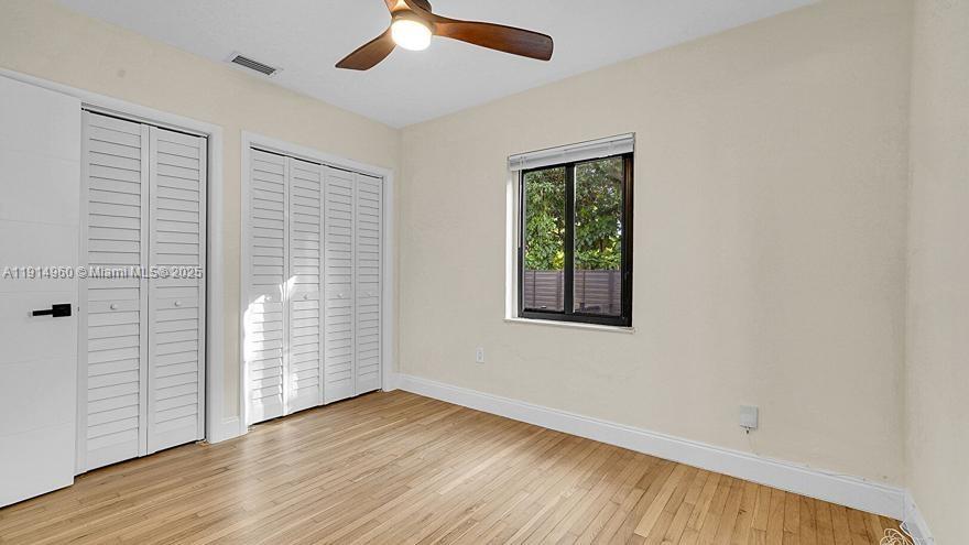 3764 Southwest 27th Lane, Unit 3762 Miami, FL 33134 - Photo 26 of 31 an empty room with wooden floor chandelier fan and windows