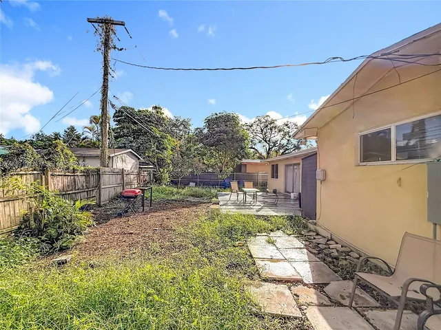 a backyard of a house with large trees and covered by side of house