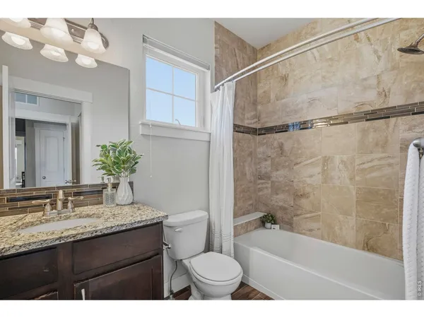 a bathroom with a granite countertop sink toilet a mirror and shower