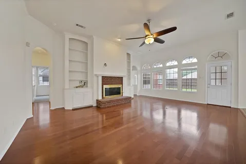 a view of an empty room with window and wooden floor