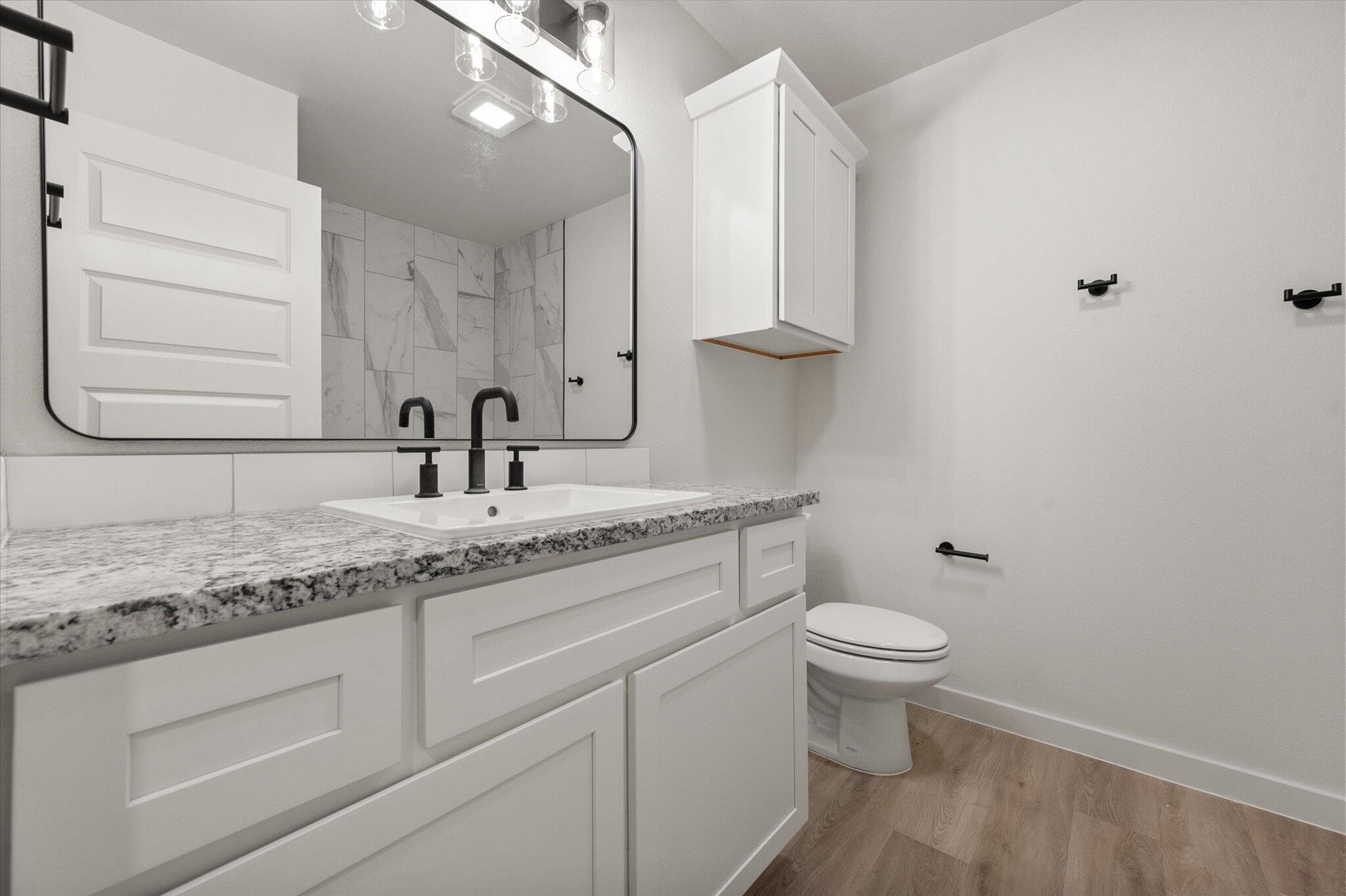 5309 Remington Avenue Lubbock, TX 79407 - Photo 19 of 22 a bathroom with a granite countertop sink a toilet and a mirror