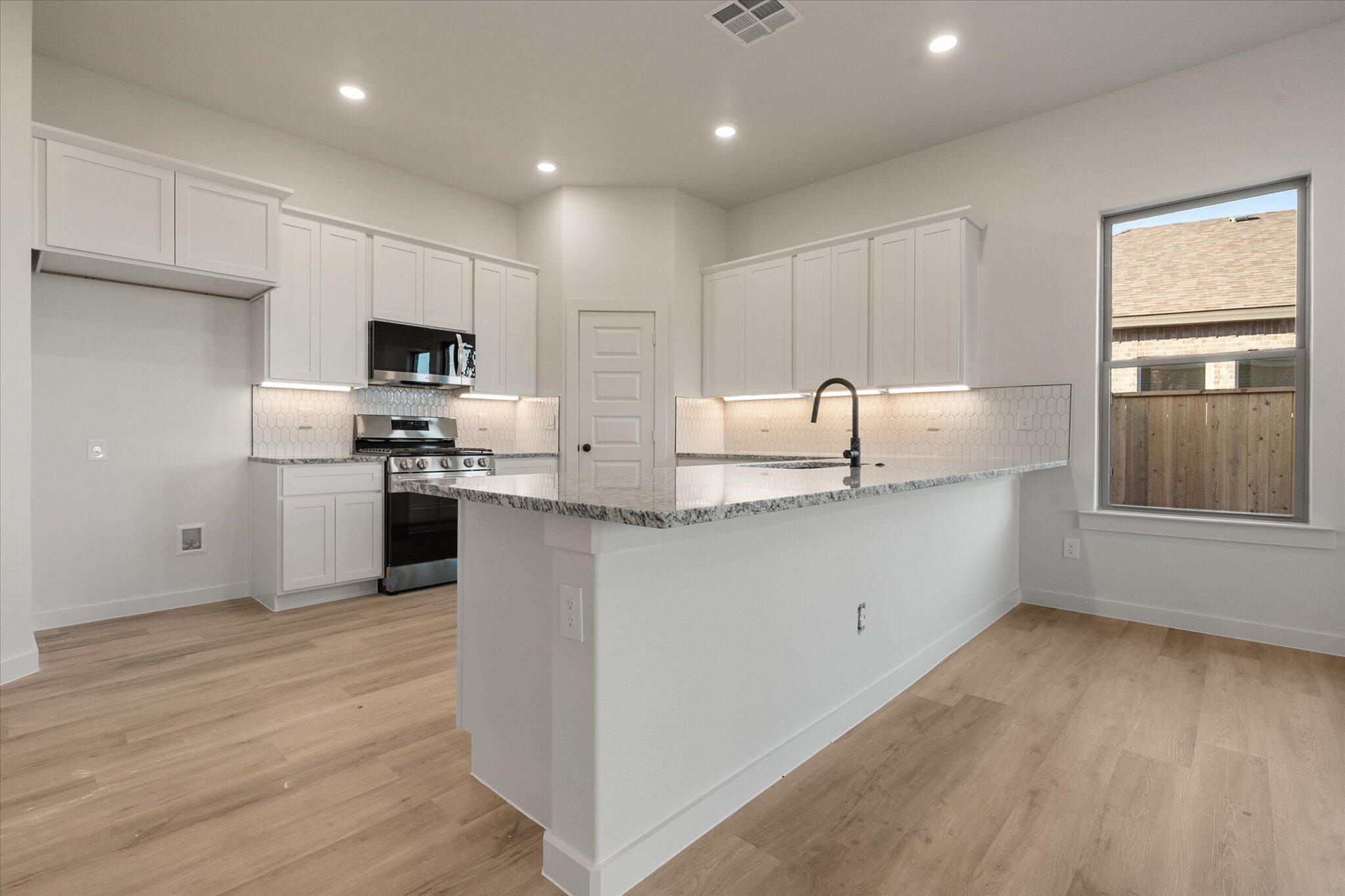 5309 Remington Avenue Lubbock, TX 79407 - Photo 5 of 22 a kitchen with kitchen island granite countertop a sink cabinets and stainless steel appliances