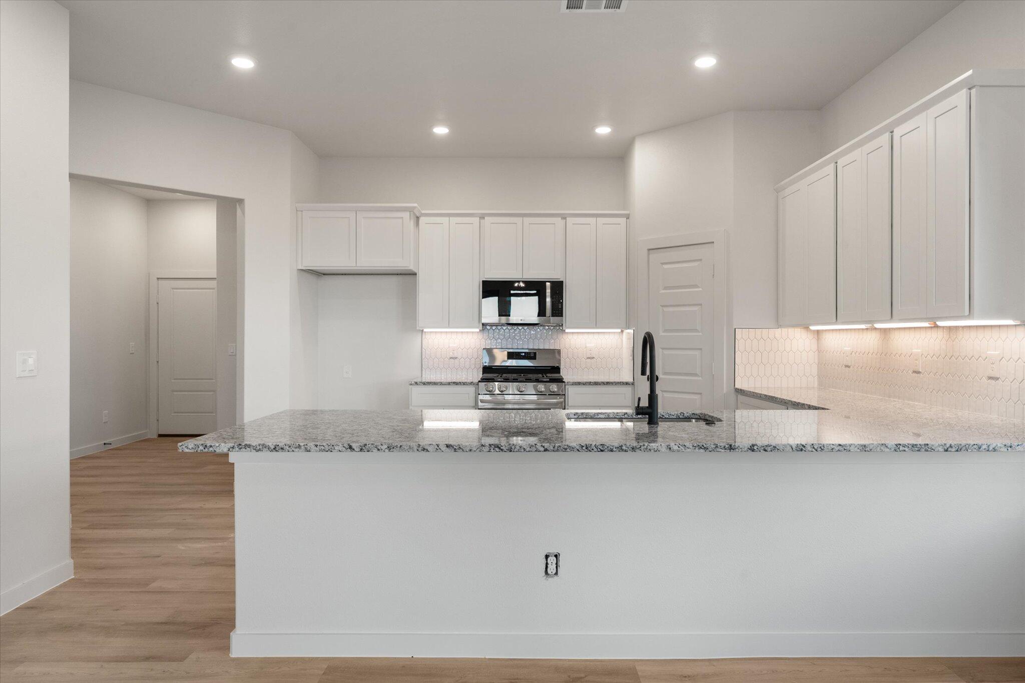5309 Remington Avenue Lubbock, TX 79407 - Photo 6 of 22 a kitchen with granite countertop a refrigerator and white cabinets