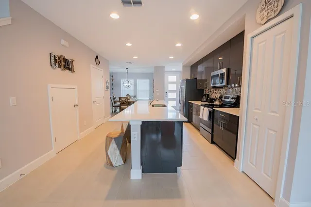 a kitchen with stainless steel appliances granite countertop a refrigerator a stove and a sink with wooden floor