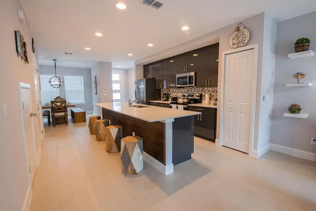 a kitchen with stainless steel appliances kitchen island granite countertop a refrigerator and a sink