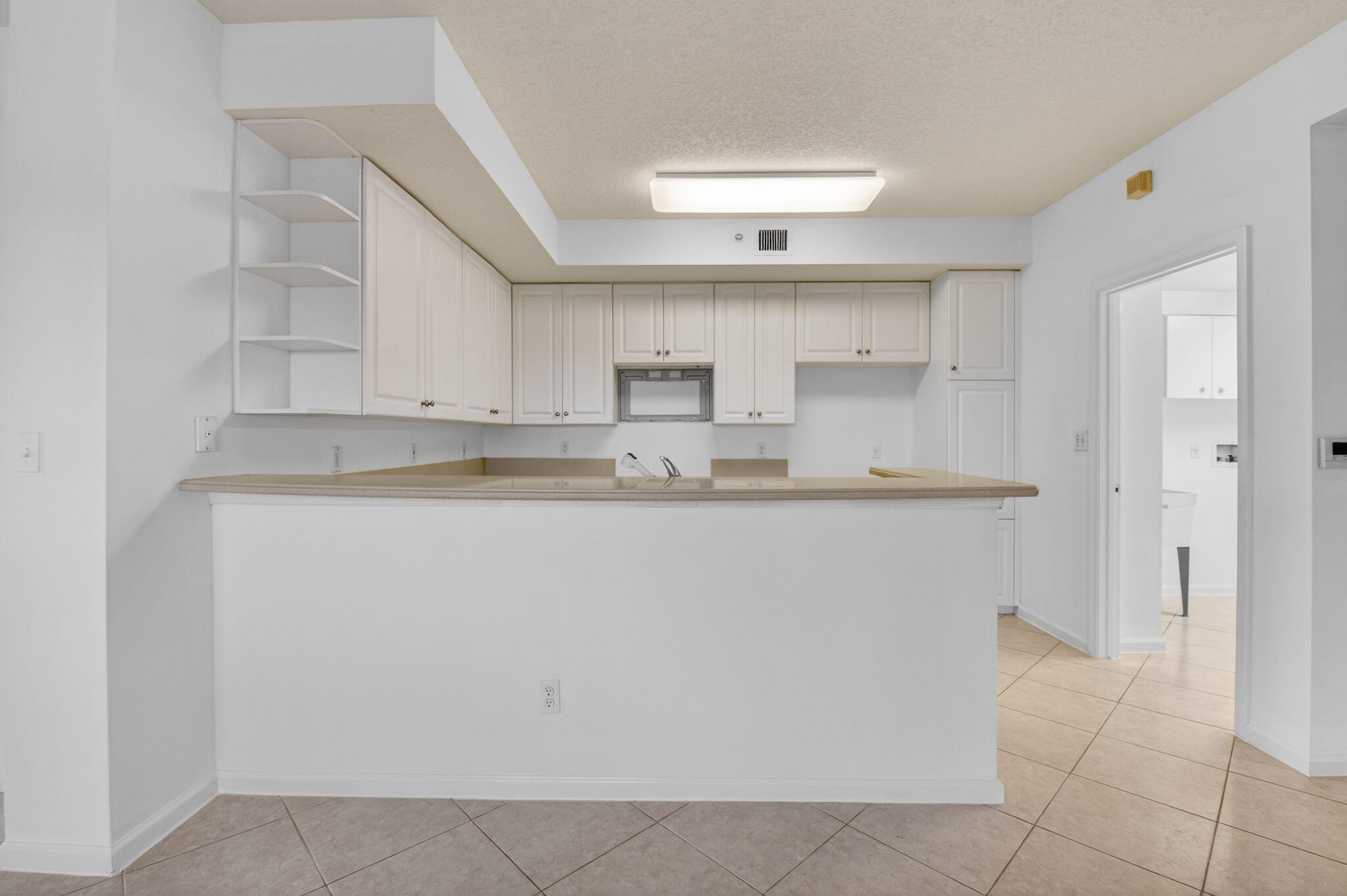 22715 Camino Del Mar, Unit 61 Boca Raton, FL 33433 - Photo 22 of 39 a kitchen with kitchen island white cabinets and refrigerator