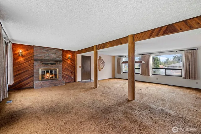 a view of an empty room with a fireplace and windows