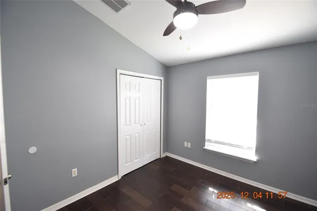 an empty room with wooden floor closet and windows