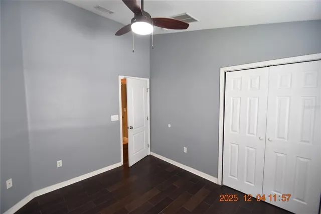 an empty room with wooden floor closet and fan
