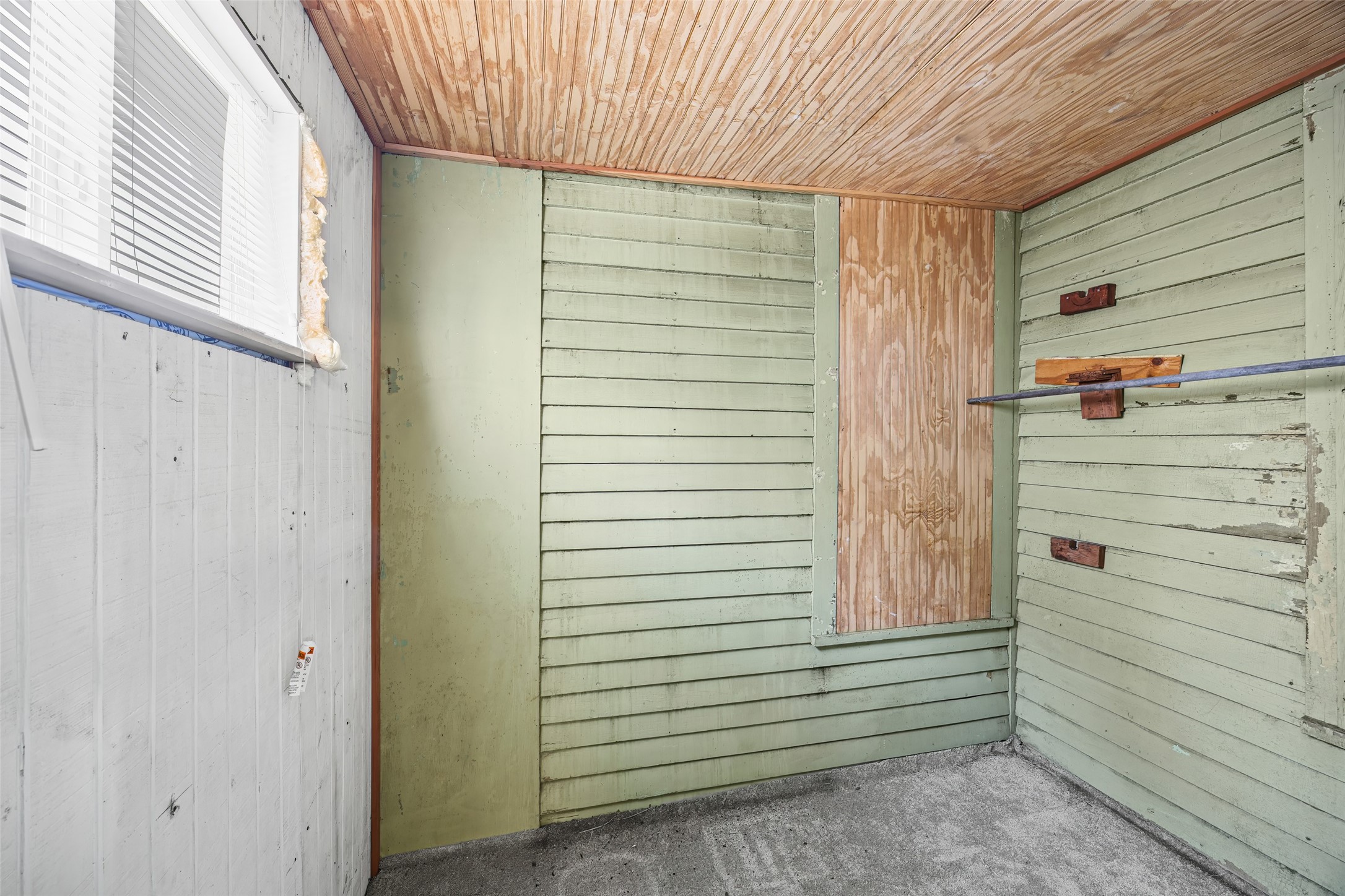 1214 Edwards Street Houston, TX 77007 - Photo 20 of 34 This room features rustic wooden paneling and a small window with blinds. It has a simple, unfinished look, offering potential for customization or storage use.