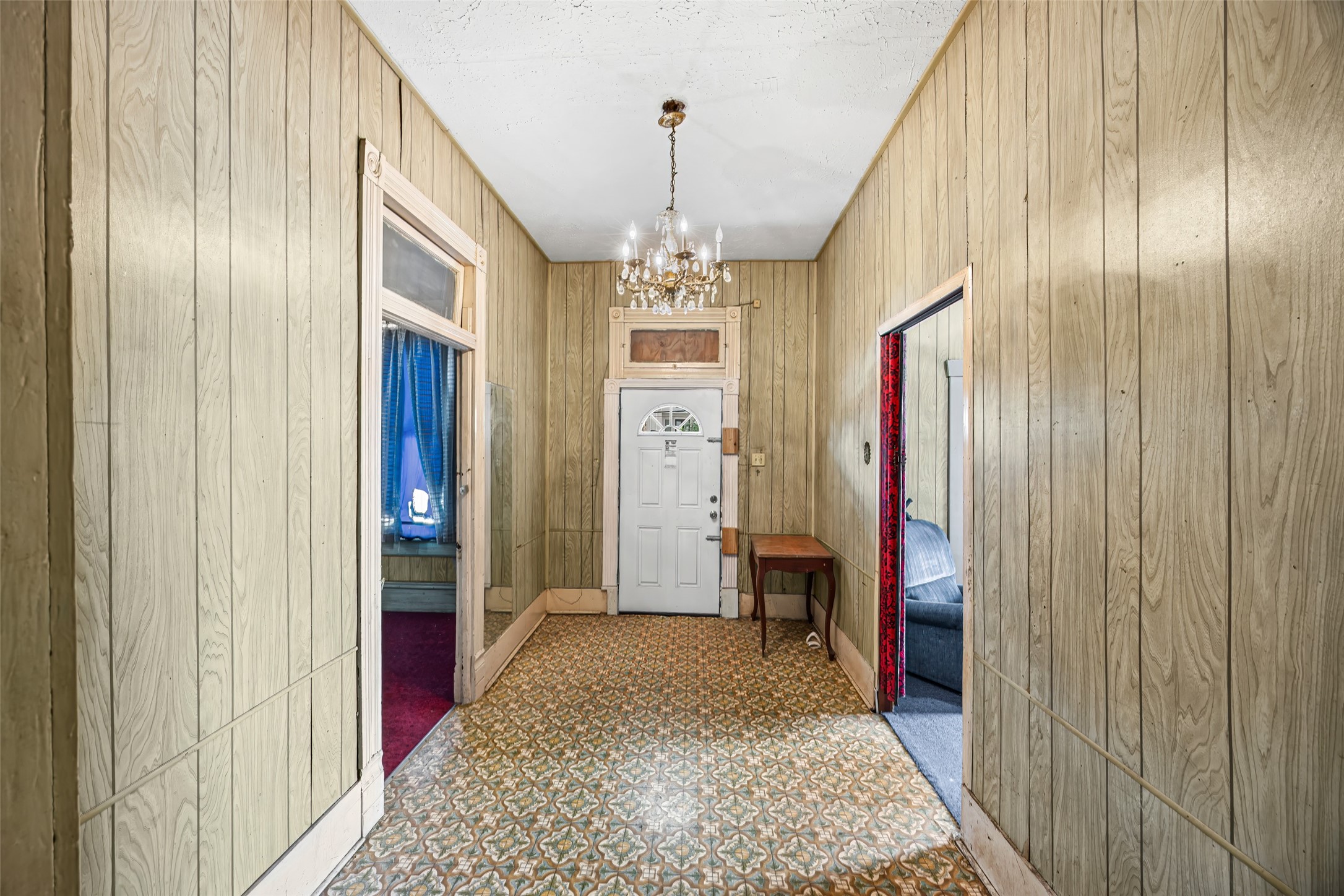 1214 Edwards Street Houston, TX 77007 - Photo 26 of 34 This photo showcases a hallway with wood-paneled walls, patterned flooring, and a chandelier. There are three doorways leading to adjoining rooms, giving the space a vintage and cozy feel.