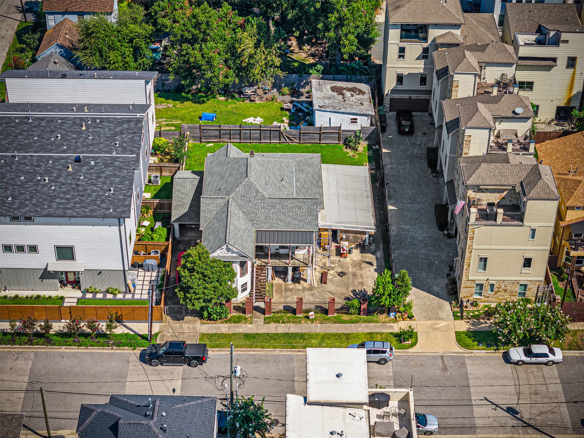 1214 Edwards Street Houston, TX 77007 - Photo 32 of 34 This aerial photo showcases a residential property in an urban area. The house has a unique roof design, a small front yard, and a spacious driveway. It's surrounded by modern multi-story homes, indicating a developed neighborhood.