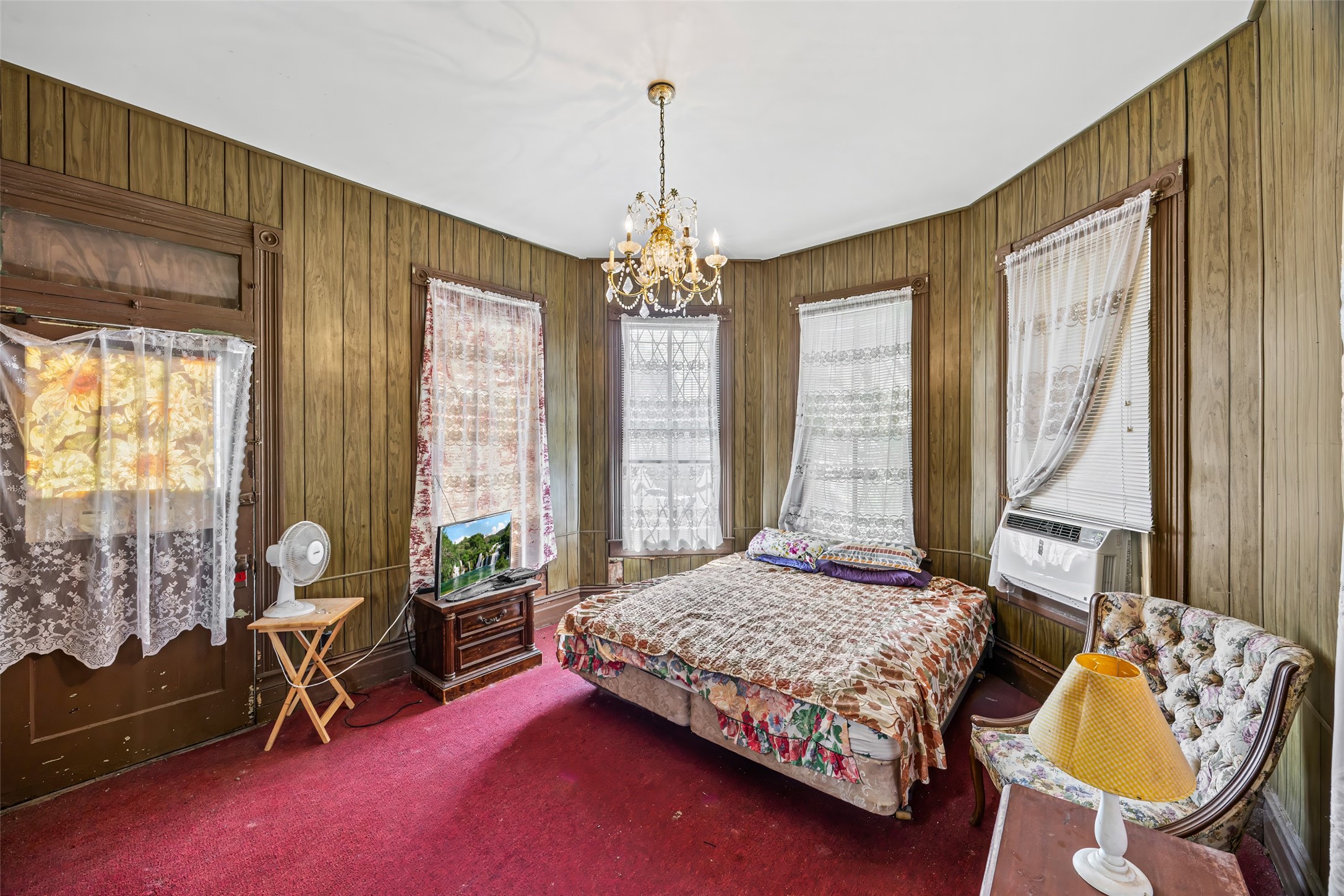 1214 Edwards Street Houston, TX 77007 - Photo 10 of 34 Step into timeless charm with this primary bedroom, featuring early 1900s classic color trends, enhanced by rich wood paneling and a vintage chandelier.
