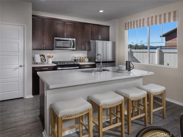 a kitchen with stainless steel appliances granite countertop a table chairs stove microwave and cabinets