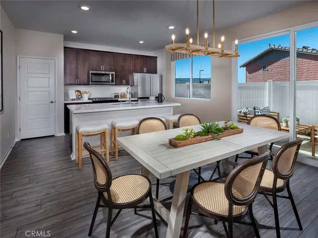 a kitchen with stainless steel appliances a dining table chairs refrigerator and microwave