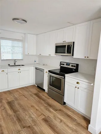 a kitchen with white cabinets stainless steel appliances and sink