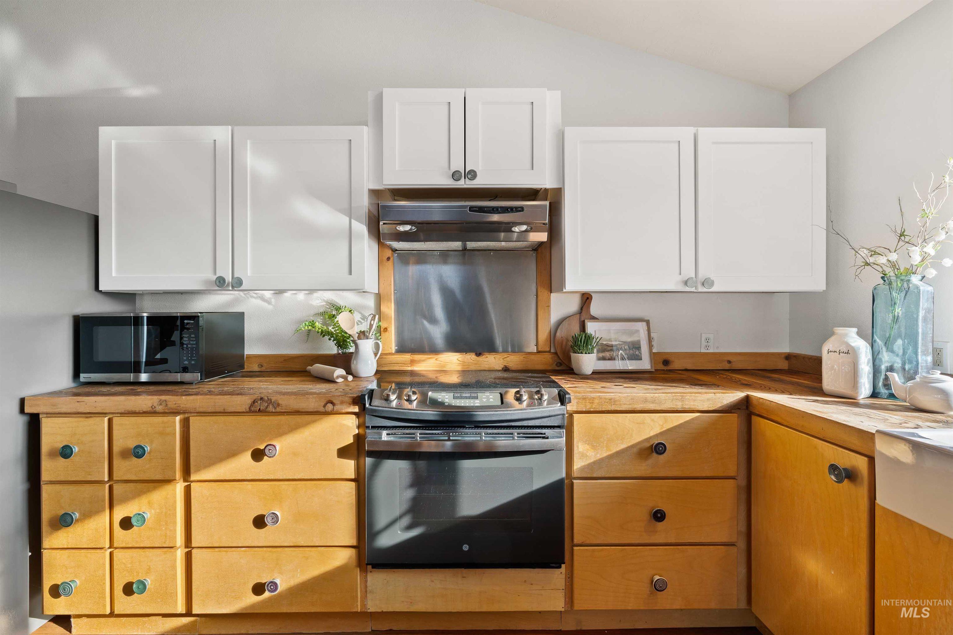 853 Pottery Road Bliss, ID 83314 - Photo 10 of 50 Kitchen featuring white cabinetry, stainless steel microwave, electric stove, exhaust hood, and vaulted ceiling