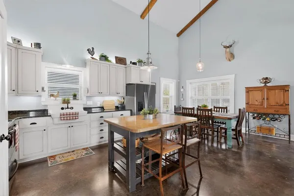 a kitchen with stainless steel appliances granite countertop a refrigerator a stove a sink dishwasher and a dining table with wooden floor