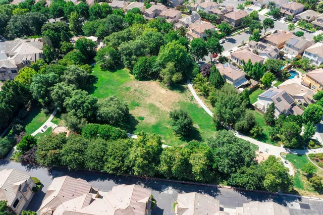 an aerial view of residential house with outdoor space and trees all around