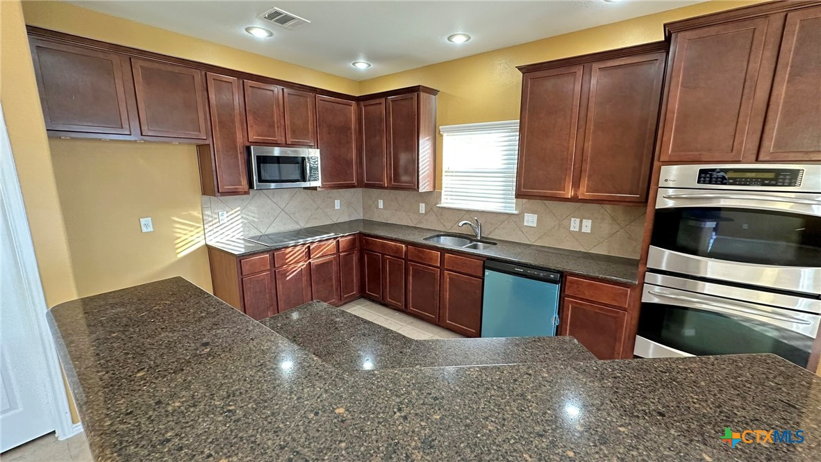 5203 Willamette Lane Killeen, TX 76549 - Photo 17 of 48 a kitchen with stainless steel appliances granite countertop a stove a sink and a microwave