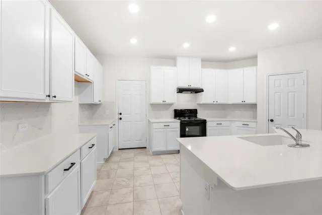 a kitchen with a sink white cabinets and white appliances