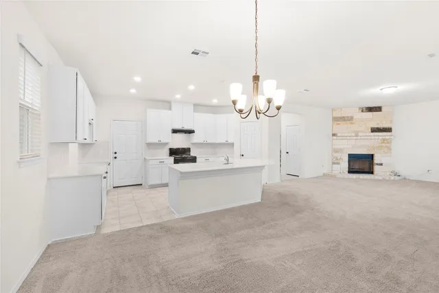 a large white kitchen with kitchen island a sink a center island and stainless steel appliances
