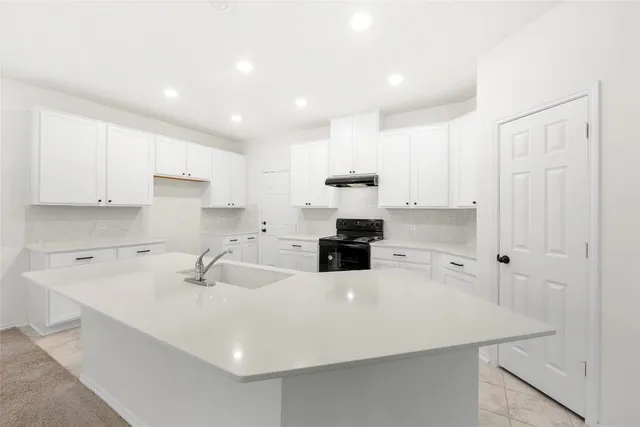 a kitchen with a sink a stove and white cabinets