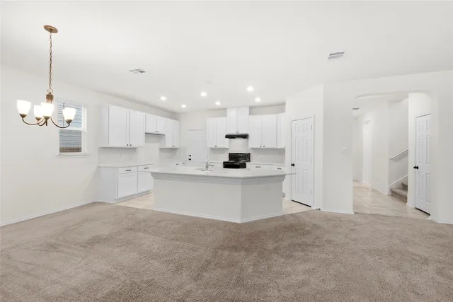 a view of a kitchen with white cabinets stainless steel appliances and a chandelier