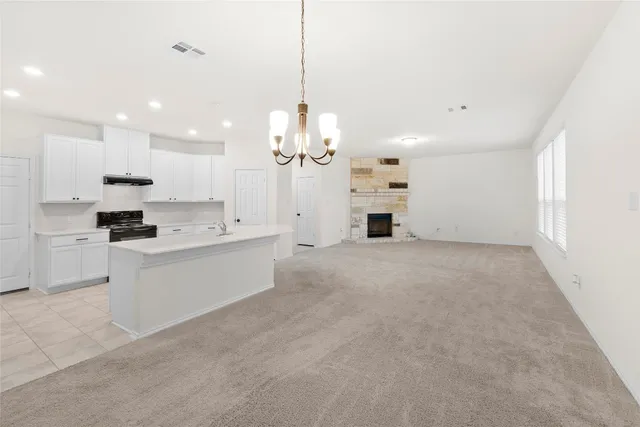 a large white kitchen with kitchen island a stove a sink a refrigerator and white cabinets
