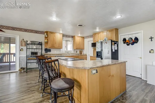 a kitchen with stainless steel appliances granite countertop a table chairs and a refrigerator