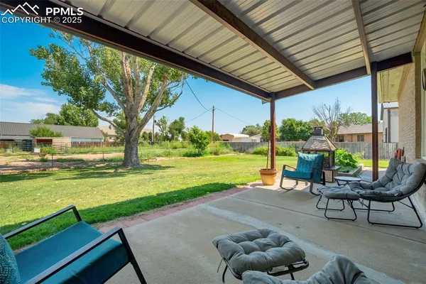 a view of a patio with lawn chairs floor to ceiling window and yard