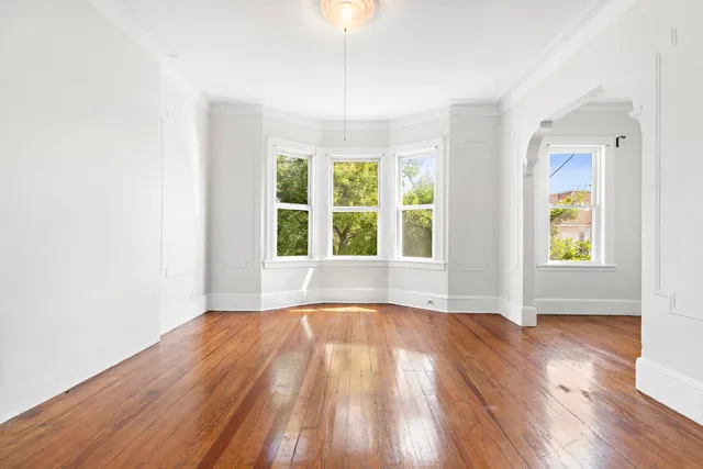 an empty room with wooden floor and windows