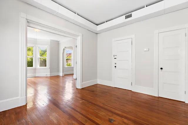 a view of an empty room with wooden floor and a window