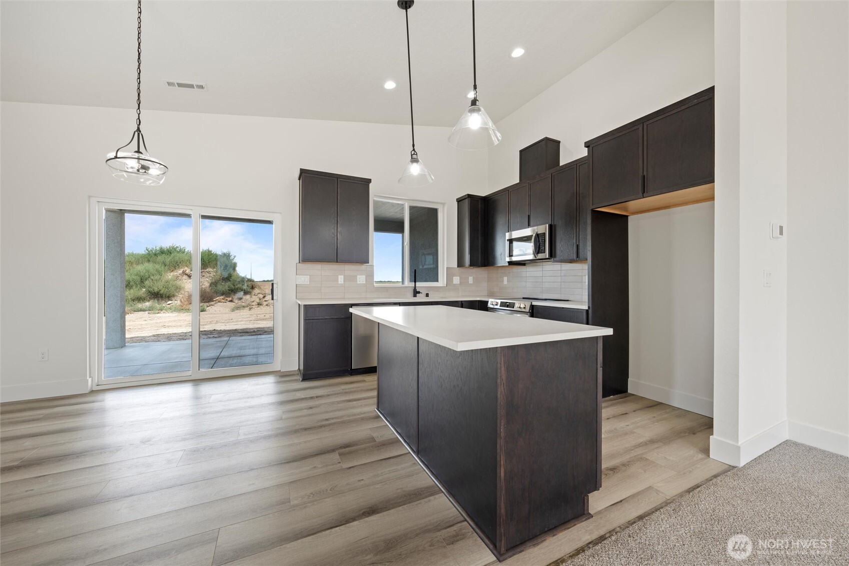 701 O Street Southwest Quincy, WA 98848 - Photo 18 of 33 a large kitchen with stainless steel appliances kitchen island a large counter top a sink a refrigerator and a wooden floor
