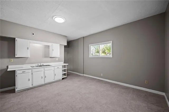 a large white kitchen with granite countertop a sink white cabinets and a window