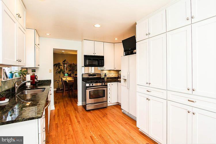 2104 Thomas View Road Reston, VA 20191 - Photo 10 of 29 a kitchen with stainless steel appliances a stove top oven a sink a refrigerator white cabinets and wooden floor