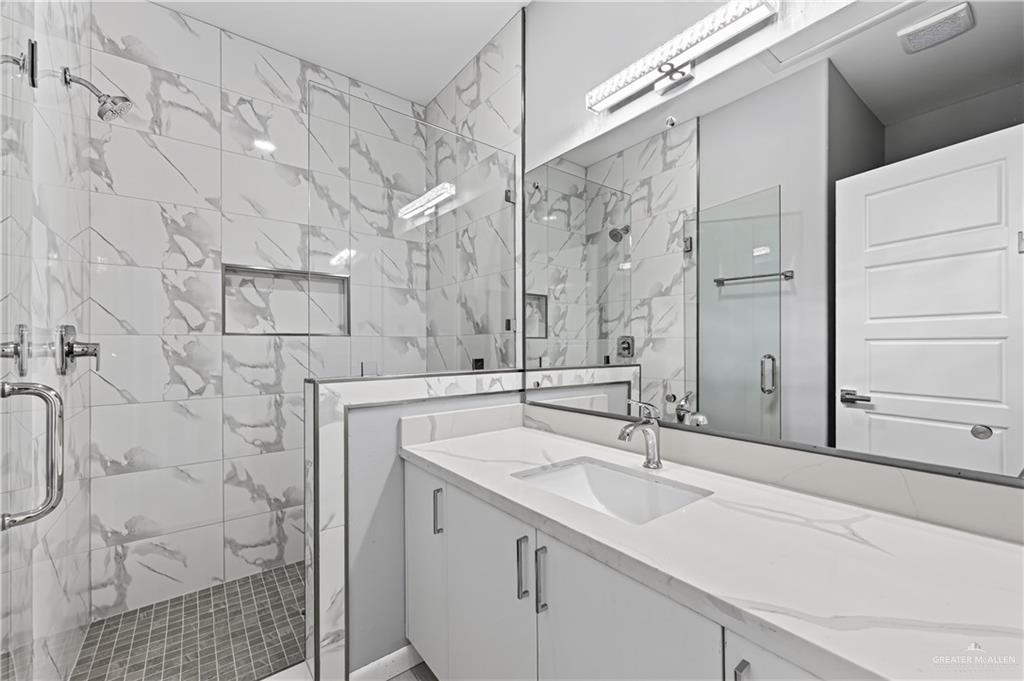 450 Sandy Road Donna, TX 78537 - Photo 9 of 15 Spacious vanity with a rectangular undermount sink, a large mirror, and an overhead light fixture