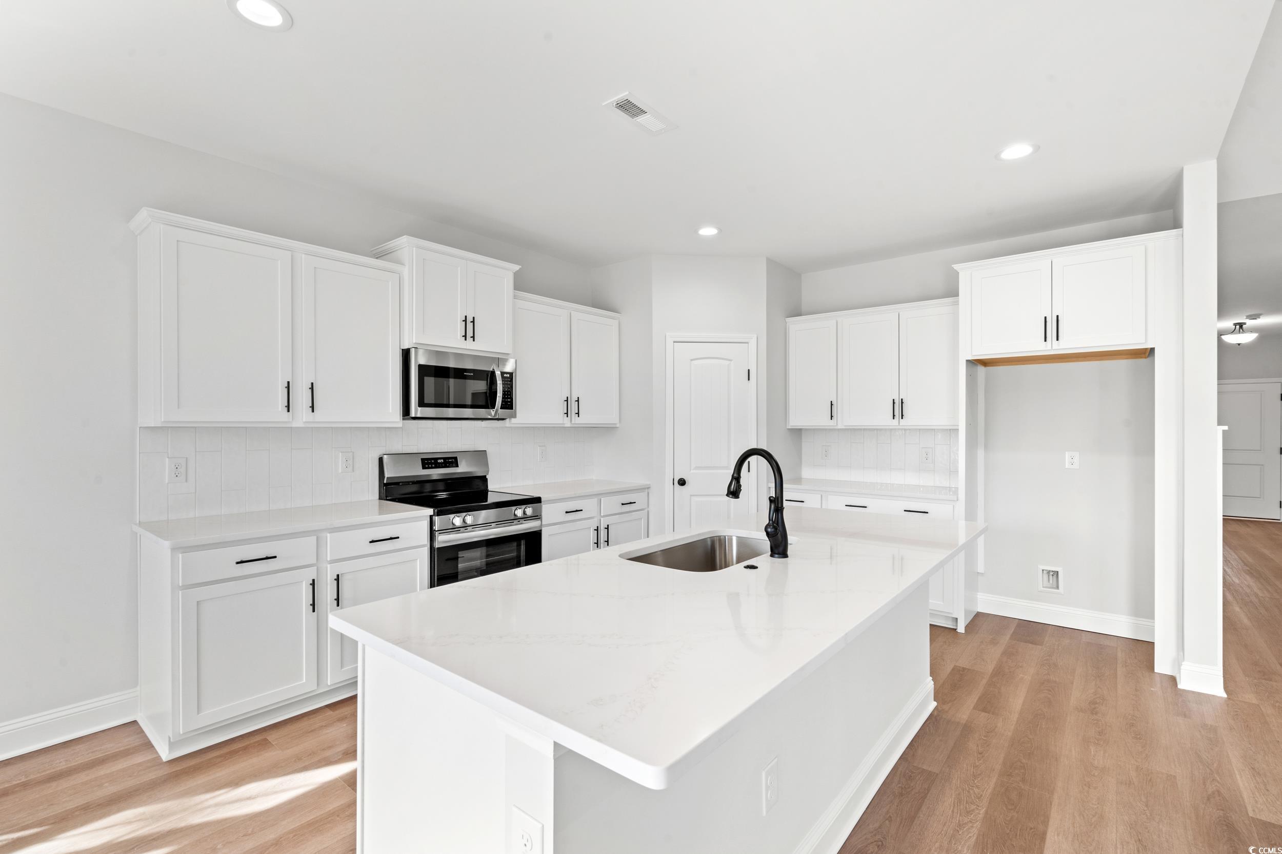 908 Francis Parker Road Georgetown, SC 29440 - Photo 6 of 37 Kitchen with tasteful backsplash, stainless steel appliances, white cabinetry, a kitchen island with sink, and light stone countertops