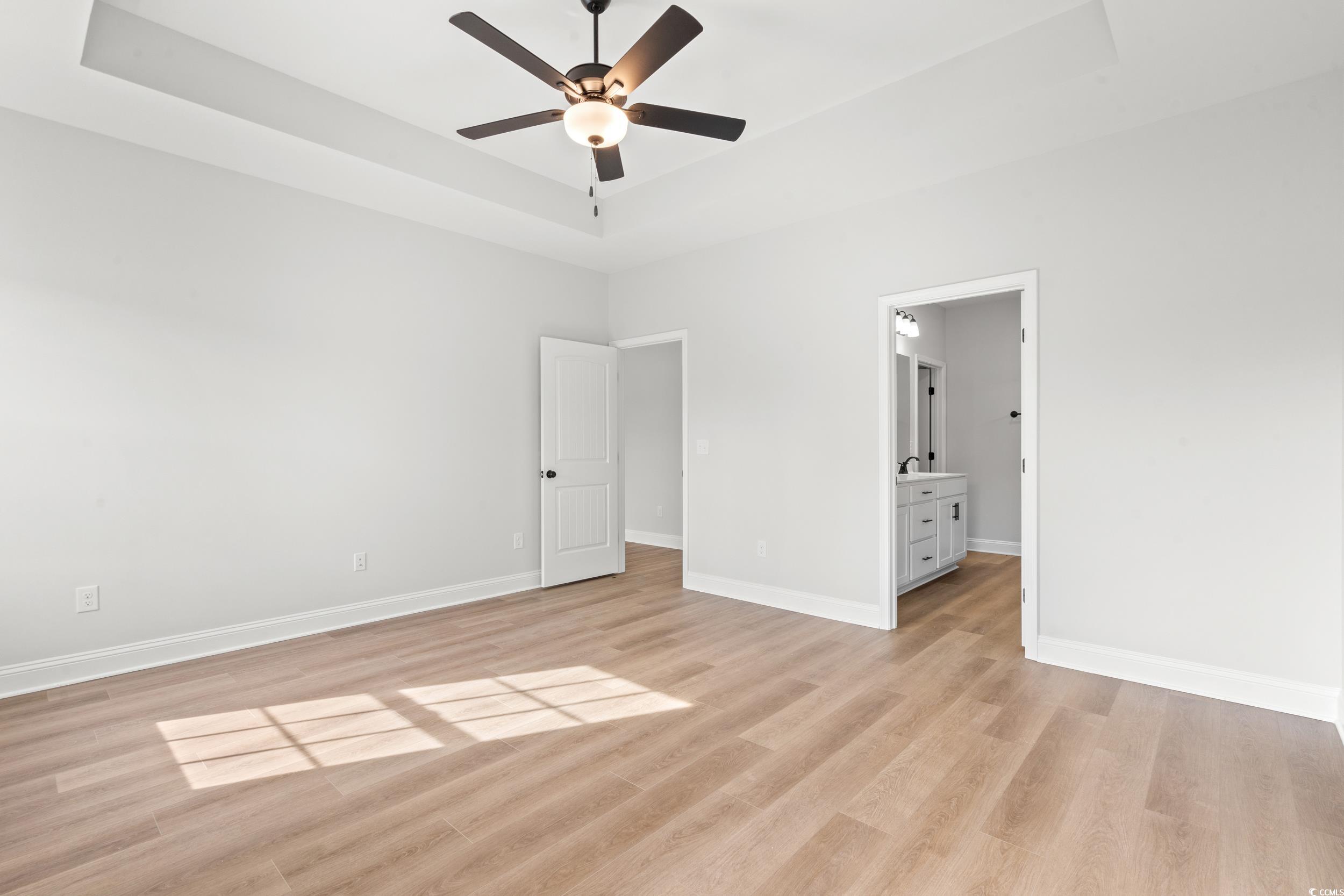 908 Francis Parker Road Georgetown, SC 29440 - Photo 9 of 37 Unfurnished bedroom featuring a tray ceiling, ceiling fan, and light wood finished floors
