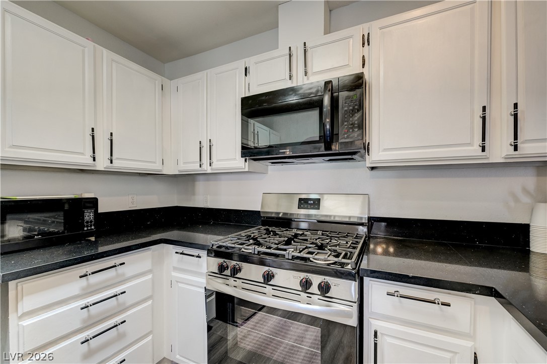 1751 East Reno Avenue, Unit 228 Las Vegas, NV 89119 - Photo 16 of 39 A well-appointed kitchen showcasing contemporary white cabinetry and sleek dark countertops.